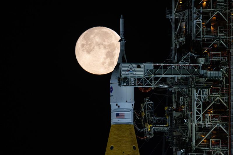 NASA's Space Launch System rocket with Orion spacecraft for the Artemis II mission stands on the launch pad at Kennedy Space Center with the full Moon rising in the background