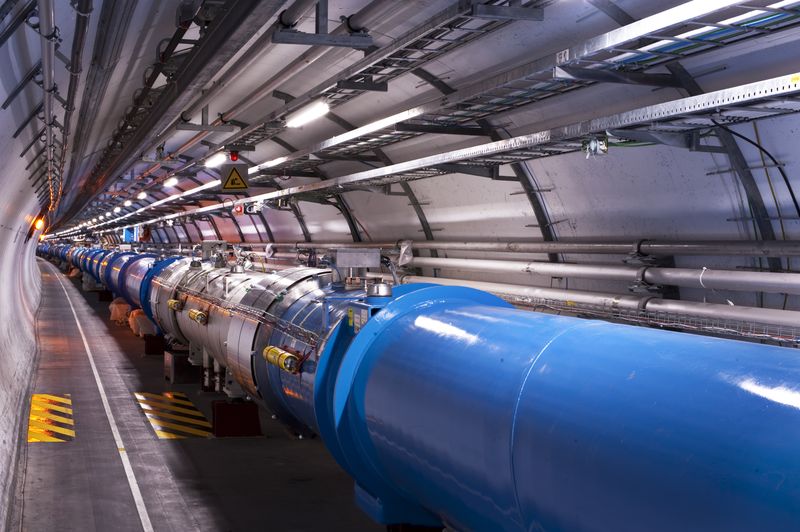 The Large Hadron Collider tunnel at CERN, showing blue superconducting dipole magnets stretching into the distance along the curved underground passage