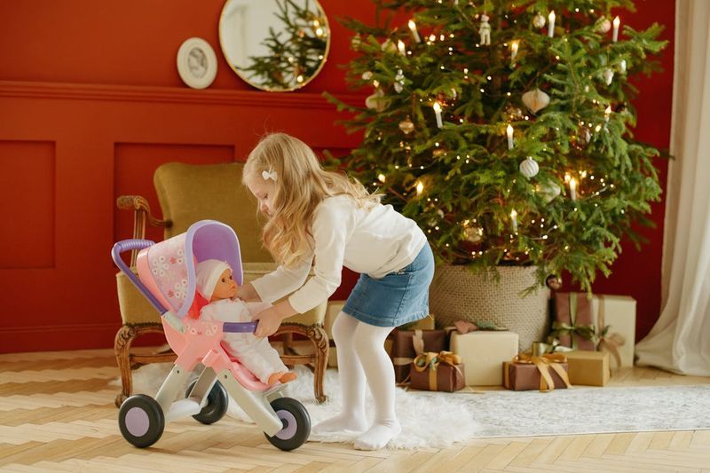 Young girl placing a baby doll into a toy stroller in a warmly decorated room