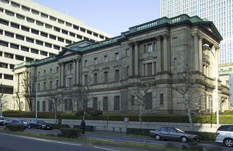 The Bank of Japan headquarters building in Nihonbashi, Tokyo, a neoclassical stone structure with columned facade, seen from across the street on a clear day