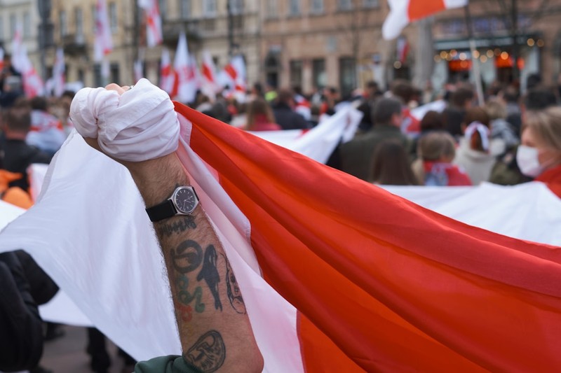 A protester holds the white-red-white Belarusian opposition flag during a Freedom Day march in Warsaw