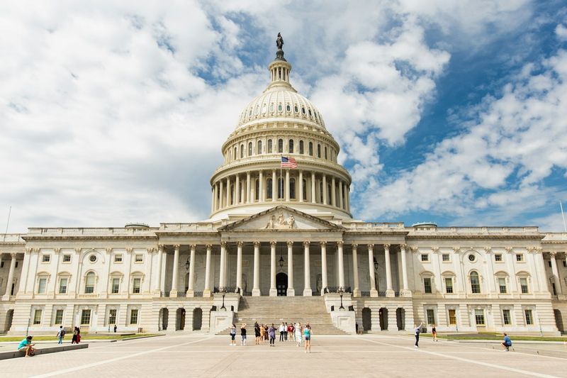 The United States Capitol building in Washington, D.C., with its iconic white dome and neoclassical facade under a partly cloudy sky