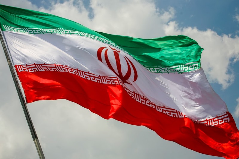 The Iranian flag waving against a cloudy sky