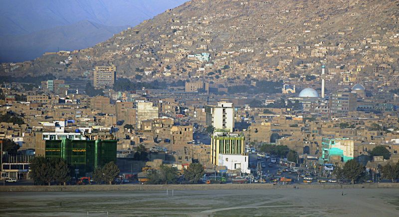 Skyline view of Kabul, Afghanistan, showing dense urban buildings and mosques against a mountainous backdrop