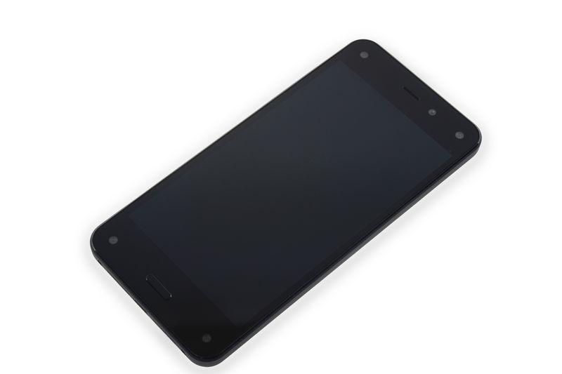 Amazon Fire Phone smartphone lying on a white background, showing its black screen and distinctive four front-facing cameras