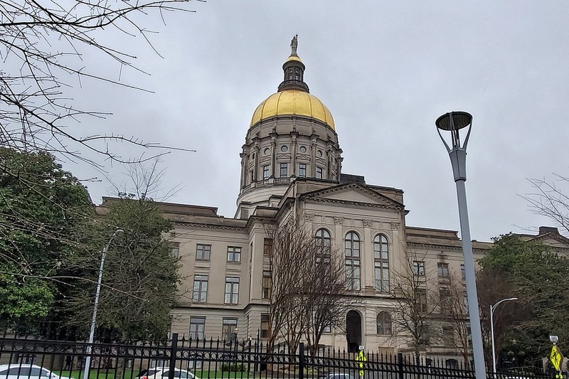 The Georgia State Capitol building in Atlanta with its distinctive gold dome, seen from street level under an overcast sky