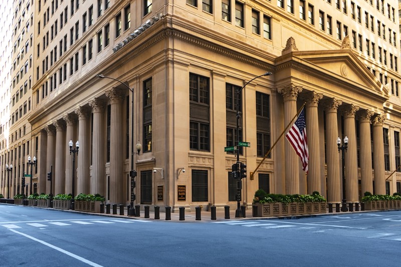 Neoclassical Federal Reserve building facade with tall columns and an American flag