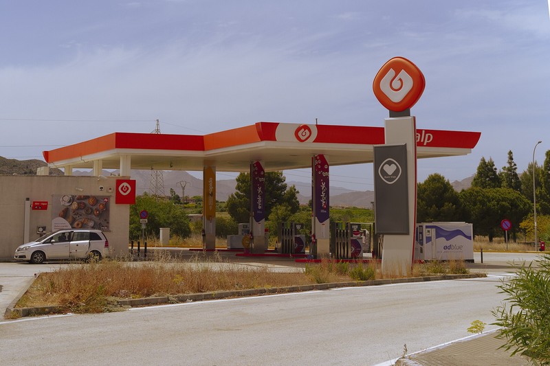 A Galp petrol station in Spain with fuel pumps under a red and white canopy, set against an arid Mediterranean landscape