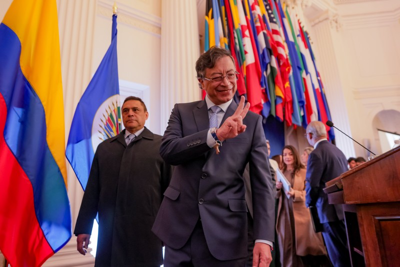 Colombian President Gustavo Petro gestures while walking past the Colombian flag and international flags during a speech event in Washington