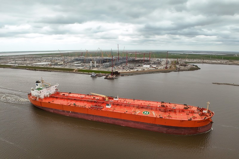 Aerial view of a large red crude oil tanker ship docked at a port facility in Port Arthur, Texas