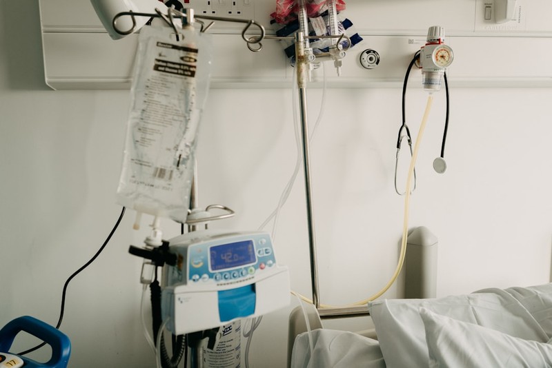 Hospital bed with intravenous drip bag and medical monitoring equipment mounted on the wall