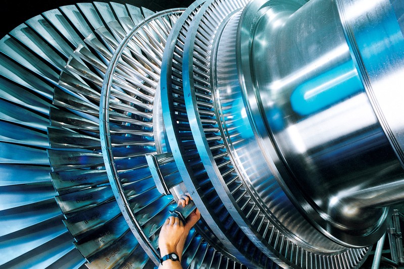 A worker installs a turbine blade on a steam turbine rotor in a Siemens factory in Germany