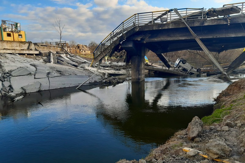 A destroyed bridge with collapsed sections and rubble, illustrating infrastructure destruction in a conflict zone