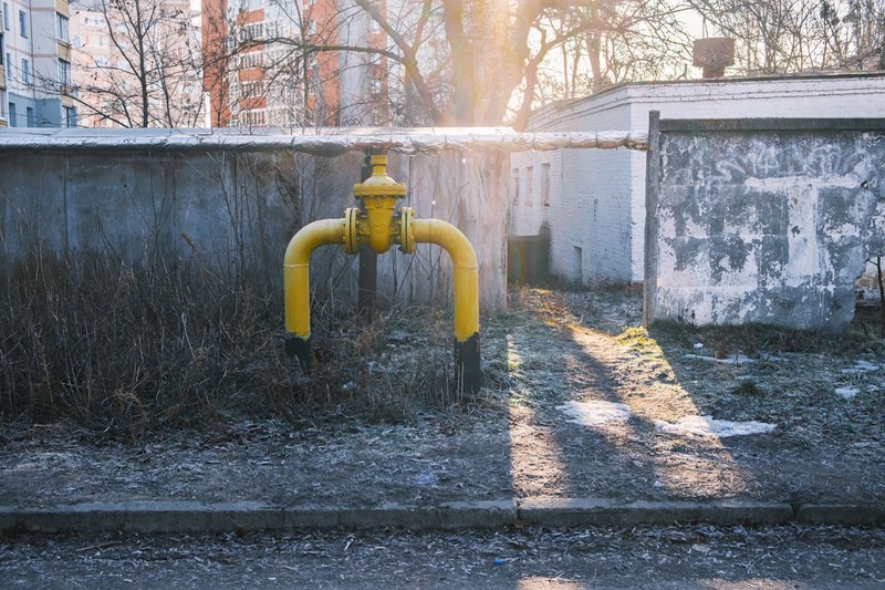 Yellow gas pipe with hand valve mounted on concrete wall