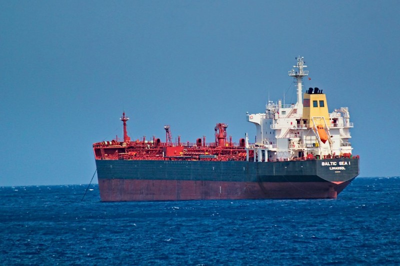 A red and white cargo tanker ship sailing on calm blue ocean under a clear sky