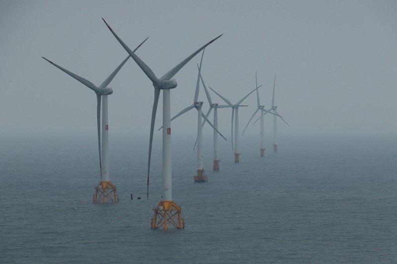 Offshore wind turbines rising from the ocean in misty conditions