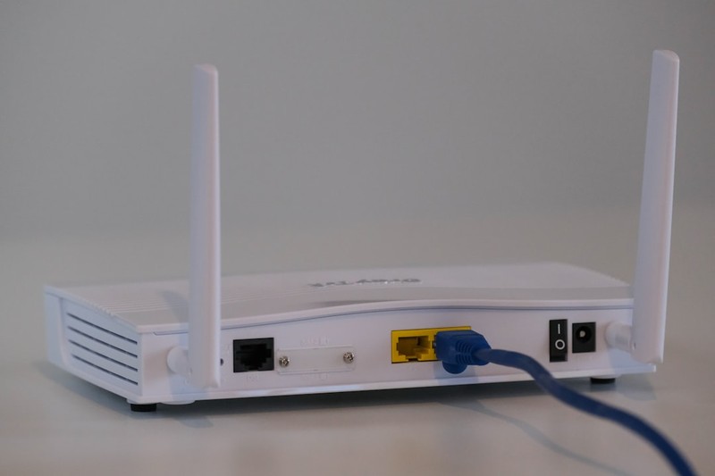 A white broadband router with an ethernet cable connected to the back port