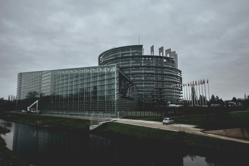 The European Parliament building in Strasbourg with its distinctive curved glass tower reflected in the water