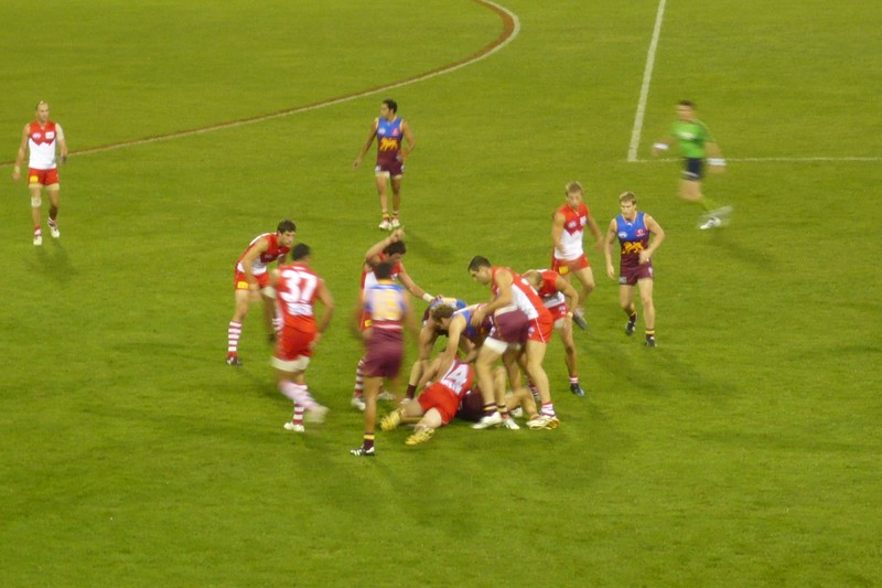 AFL match between Brisbane Lions and Sydney Swans showing players contesting for the ball on the field