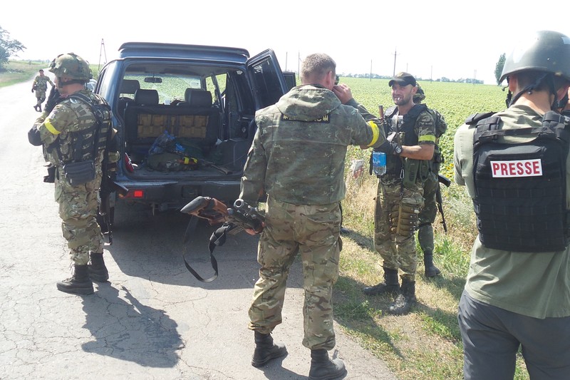 Military personnel and press near a vehicle in the Donetsk region of Ukraine