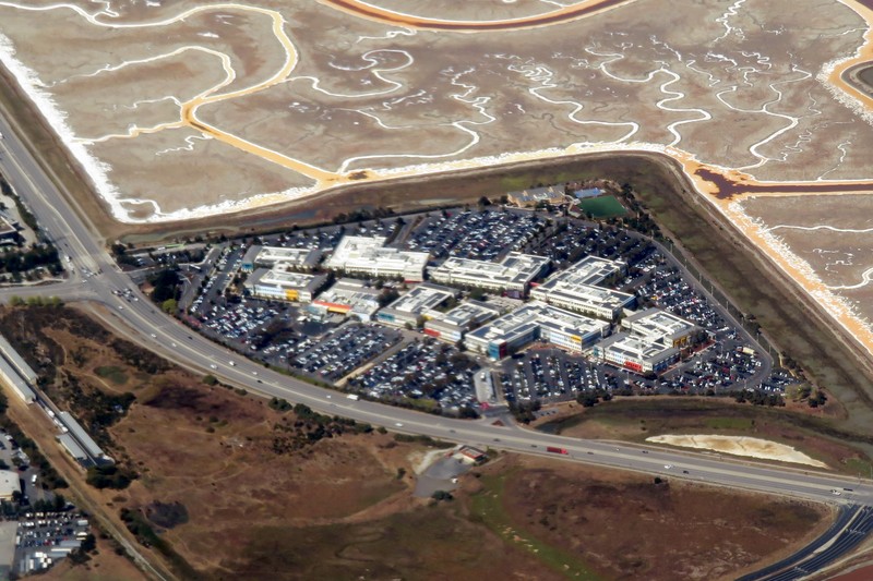 Aerial view of Meta's corporate campus in Menlo Park, California, showing office buildings, parking lots, and surrounding salt flats