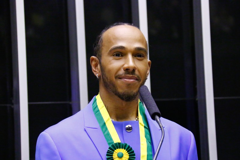 Lewis Hamilton wearing a purple suit and Brazilian honor ribbon at a ceremony
