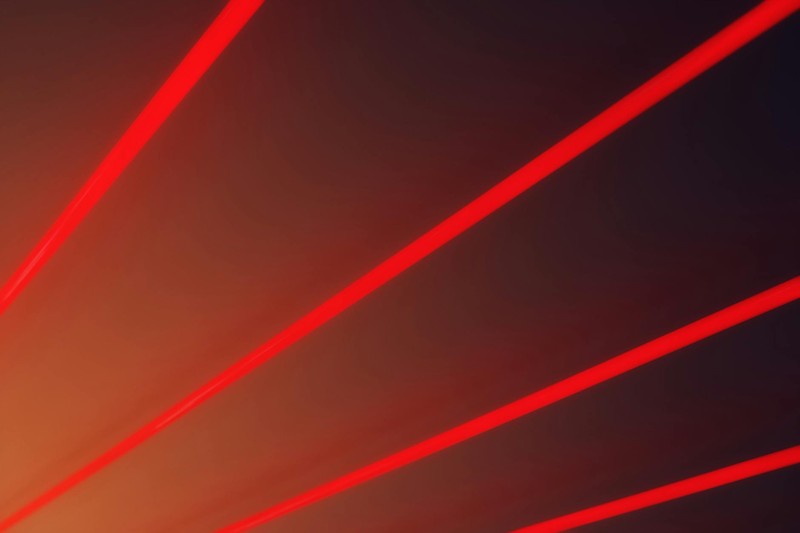 Red laser beams radiating diagonally across a dark gradient background