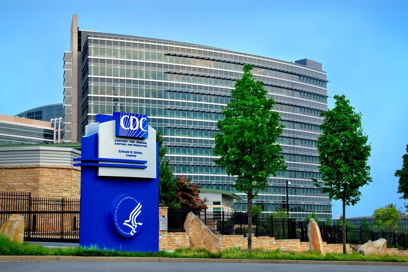The CDC headquarters building with a blue CDC sign in the foreground
