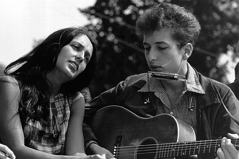 Joan Baez and Bob Dylan in an outdoor setting during the Civil Rights era