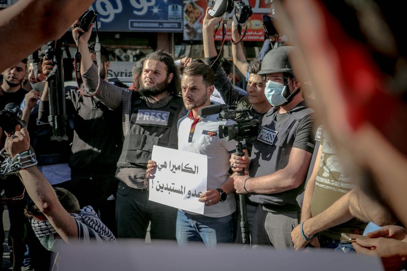 Journalists with cameras at a demonstration holding a Freedom placard with Arabic text