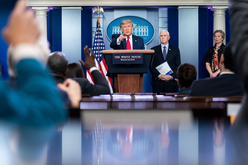 President Donald Trump speaks at a White House press briefing podium with the presidential seal visible behind him
