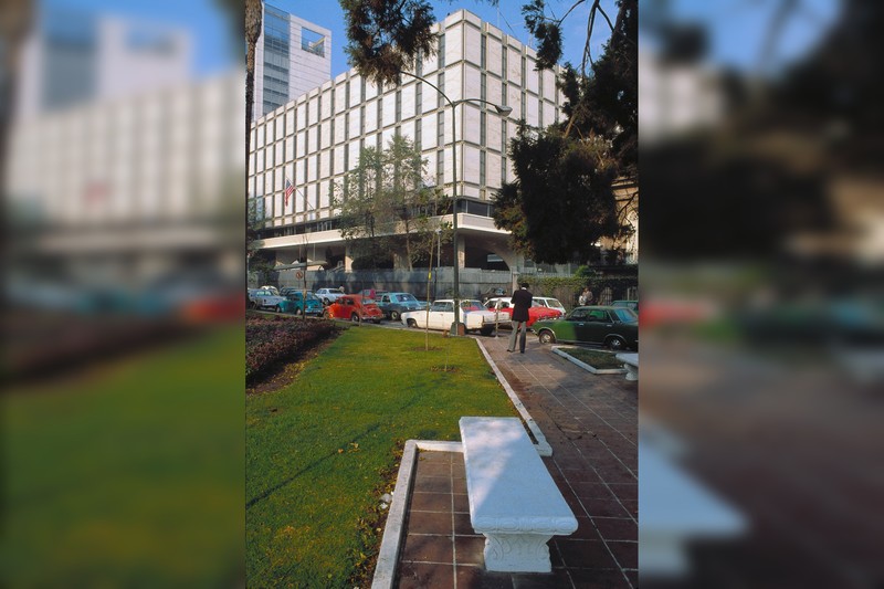 Exterior view of a modernist US government building with the American flag displayed on the facade