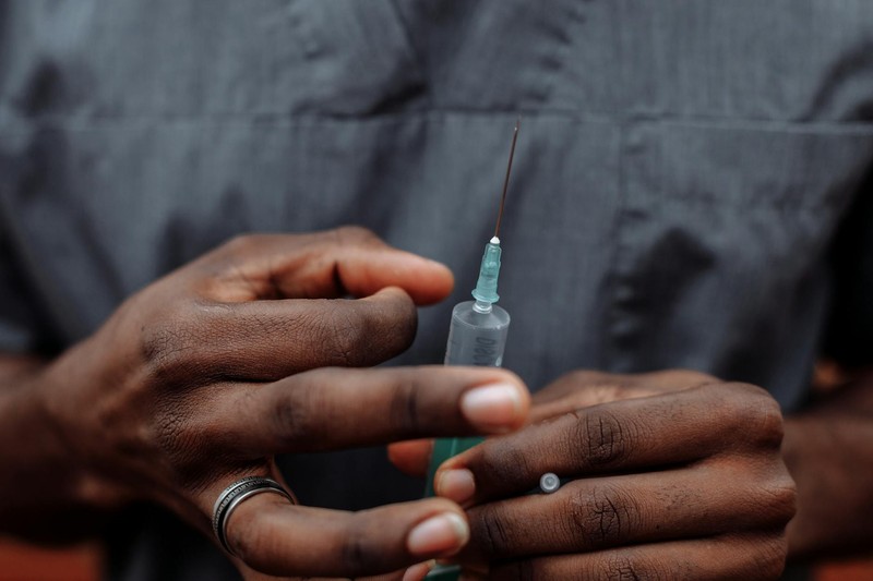 Close-up of gloved hands holding a medical syringe against a blurred background