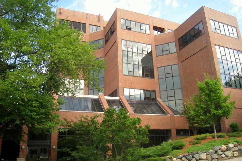 The Fletcher School of Law and Diplomacy building at Tufts University surrounded by trees under a partly cloudy sky