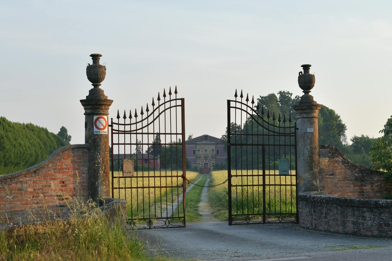 Wrought iron gates at the entrance to a secluded Italian villa surrounded by greenery