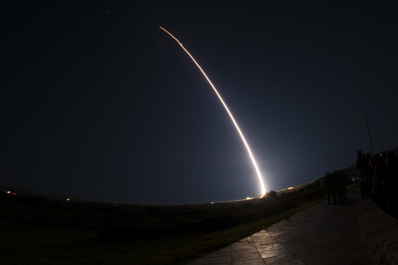 A Minuteman III intercontinental ballistic missile launches in an arcing trail of light against the night sky at Vandenberg Air Force Base, California