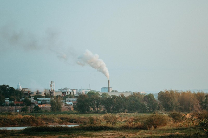 Industrial smokestack emitting smoke over a rural landscape in Vietnam