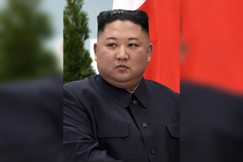 North Korean leader Kim Jong-un in a formal setting with the North Korean national flag visible behind him