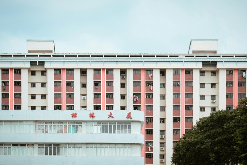 A multi-story residential apartment building in China with Chinese characters on its facade, viewed under an overcast sky