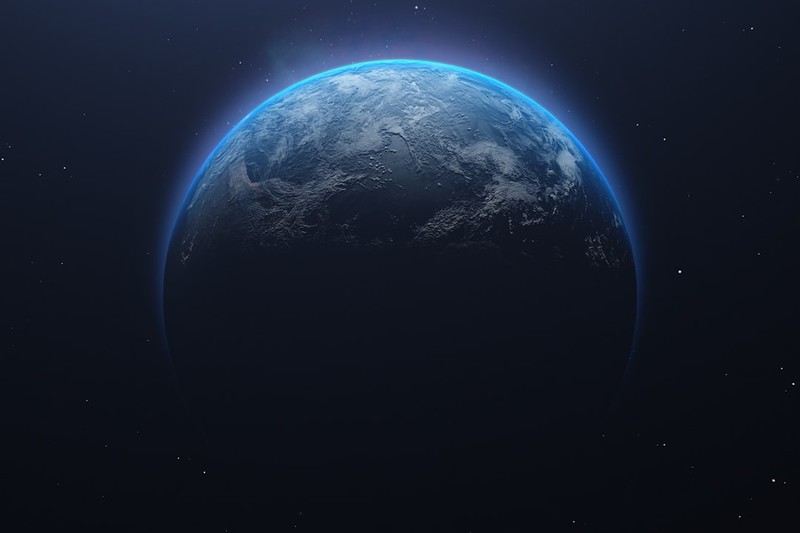 Earth seen from space, partially illuminated against the dark cosmos with a glowing blue atmospheric halo