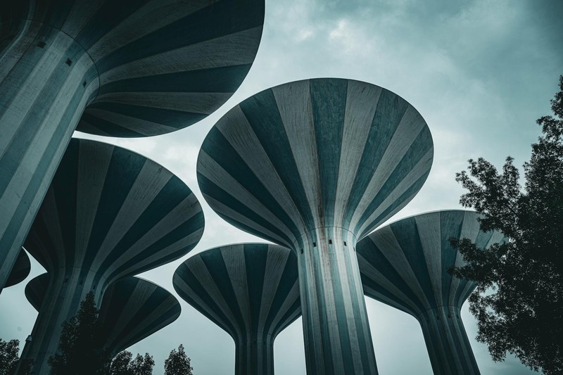 Kuwait's iconic water towers rise against a moody, overcast sky, framed by trees