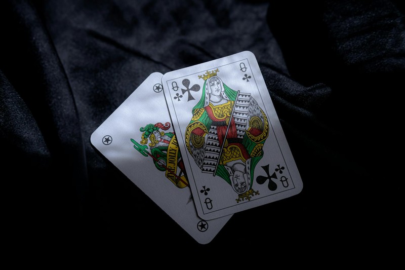 Queen of Clubs playing card on dark fabric