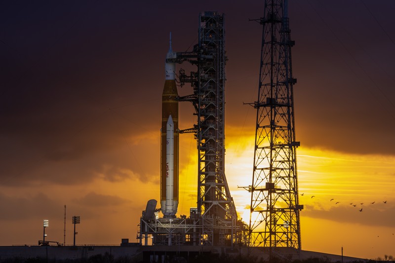NASA's Space Launch System rocket silhouetted against a vibrant sunset on the launch pad at Kennedy Space Center