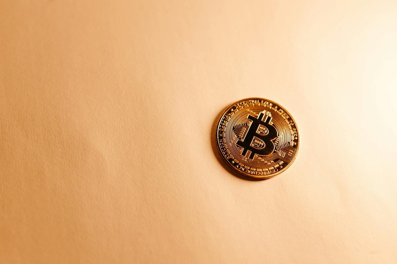 A gold Bitcoin cryptocurrency coin on a neutral background