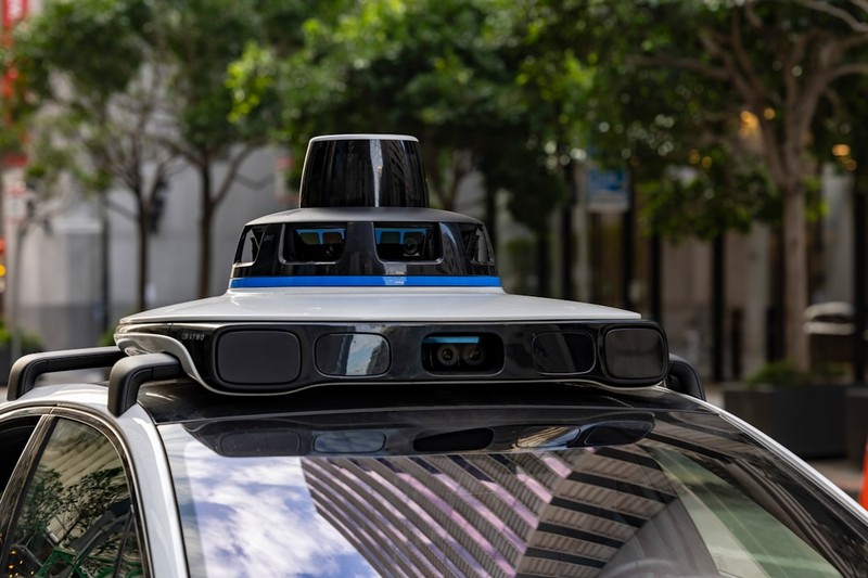 A self-driving car with LiDAR sensor array on its roof driving on a city street