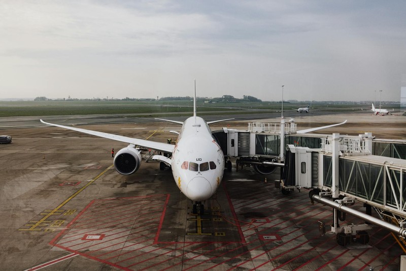 A commercial jet aircraft docked at an airport boarding gate under overcast skies