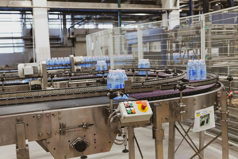 Blue water bottles moving along a curved conveyor belt in an automated factory