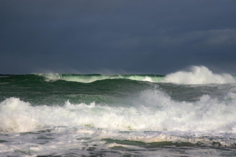 Powerful ocean waves crashing under a dark, stormy sky