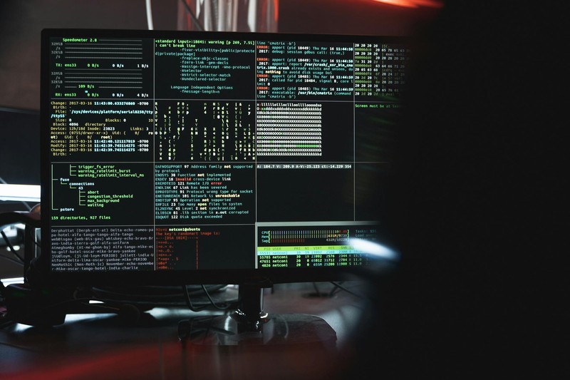 Close-up of a computer monitor displaying lines of code and security data in a dark room