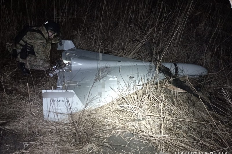 A recovered Russian Shahed-136 drone inspected by military personnel in a nighttime field in Ukraine